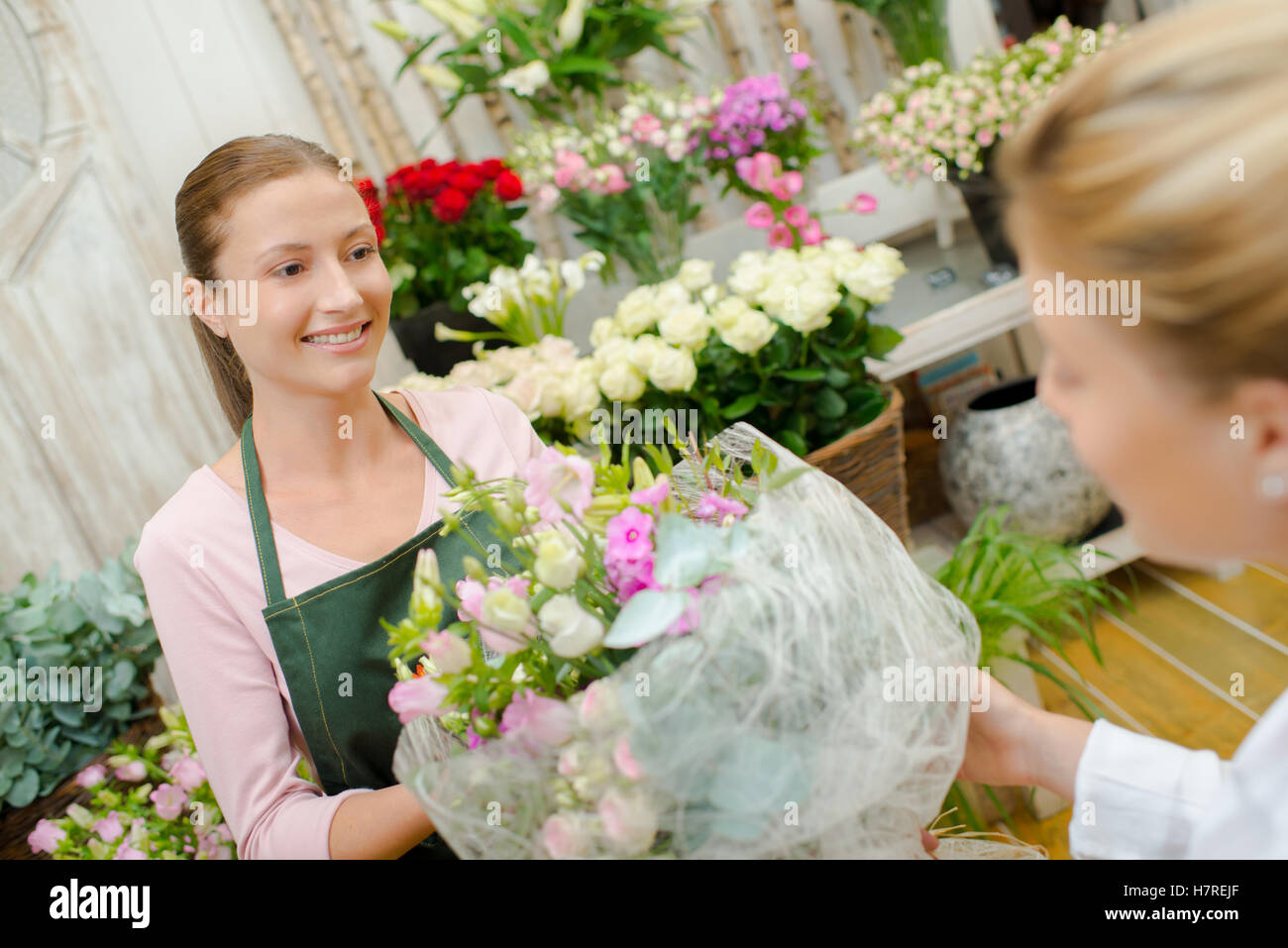 Florist giving arrangement of flowers to customer Stock Photo Alamy