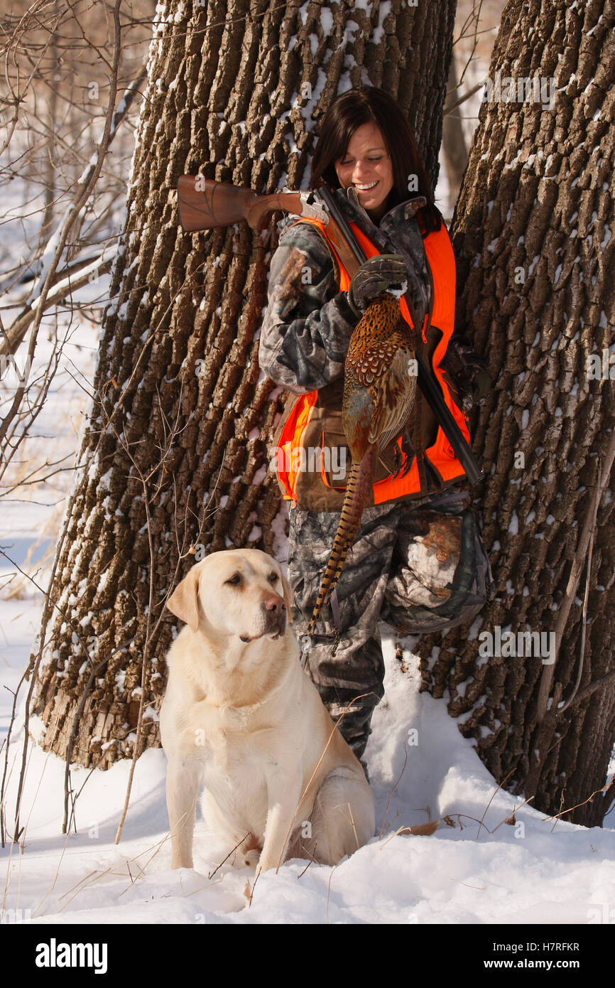 Female Pheasant Hunter In Winter With Yellow Lab Stock Photo