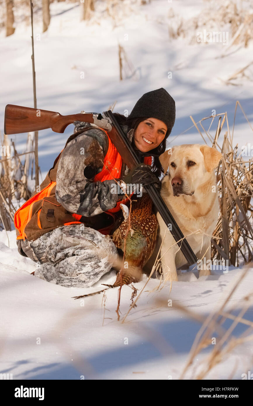 Female Pheasant Hunter In Winter With Yellow Lab Stock Photo