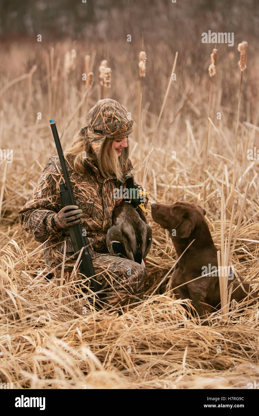 Female Waterfowl Hunter With Rifle And Rusty Yellow Lab Stock Photo