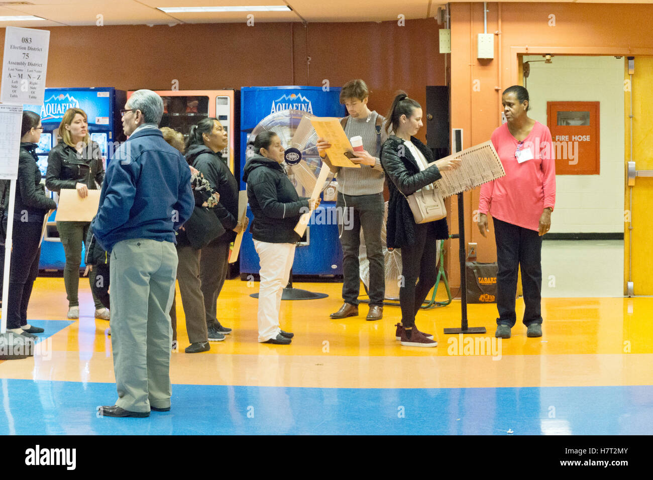 New York, USA. 8th November, 2016. group of typical multi ethnic New Yorkers in line to scan their votes at Park West Vocational High School cheerful cafeteria in Hells Kitchen neighborhood. The lines for registration & scanners were longer than at kiosks for filling out ballots.Park West High School gathers teens from many boroughs to train as cooks. It doesn't look like the kids are offered too many sweet soft drinks by the look of the vending machines. Credit:  Dorothy Alexander/Alamy Live News Stock Photo