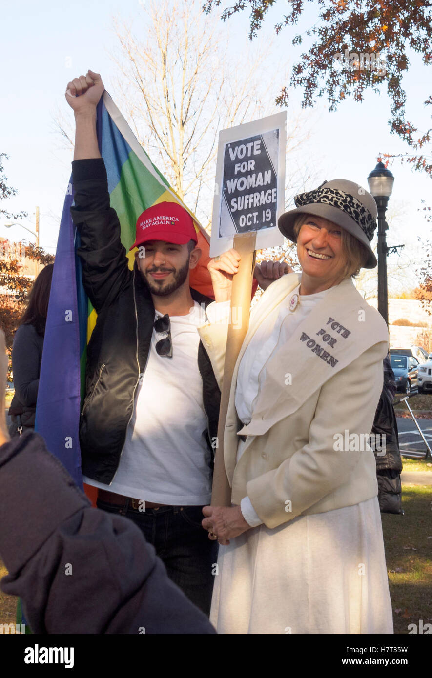 Chappaqua, NY, USA - 8 November 2016. Mary Refling of Chappaqua New York dressed as a suffragette in support of Hillary Clinton poses with J.D. Scarola of Somers, NY who holds a rainbow flag and wears a hat that says 'Make America Gay Again' after a Pantsuit Up flash mob at the Chappaqua Train Station on Election Day. Credit:  Marianne A. Campolongo/Alamy Live News Stock Photo