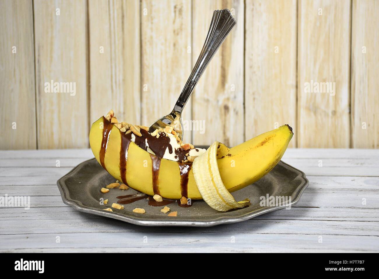 banana split sundae with dripping chocolate and cashew nuts in peeled