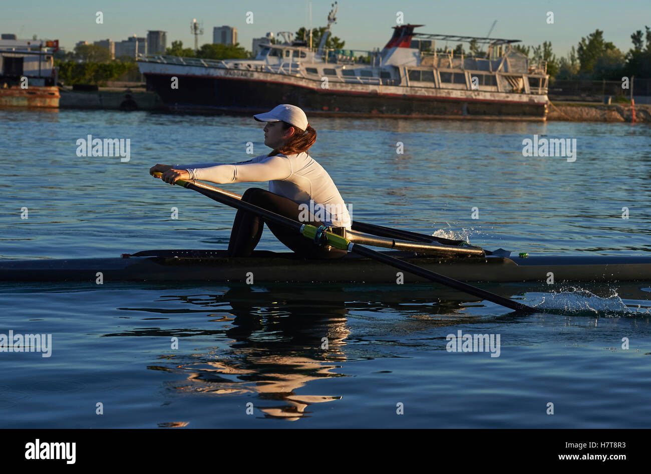 Young woman in a single scull, Hanlan Boat Club in the harbour; Toronto, Ontario, Canada Stock Photo