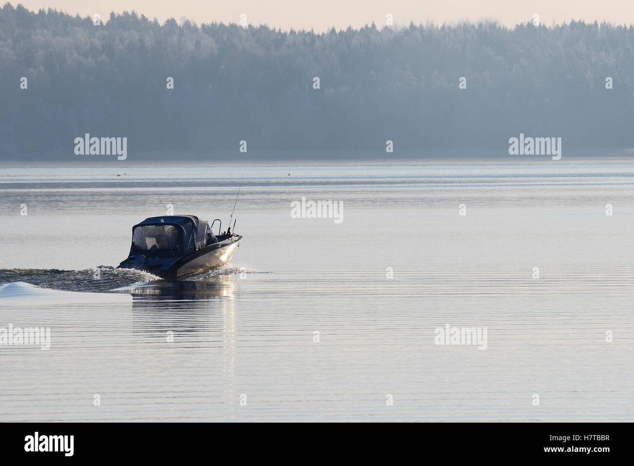 Motorboat on calm cold sea. Forest on background with rime. Photo taken in Parainen, Finland. Stock Photo