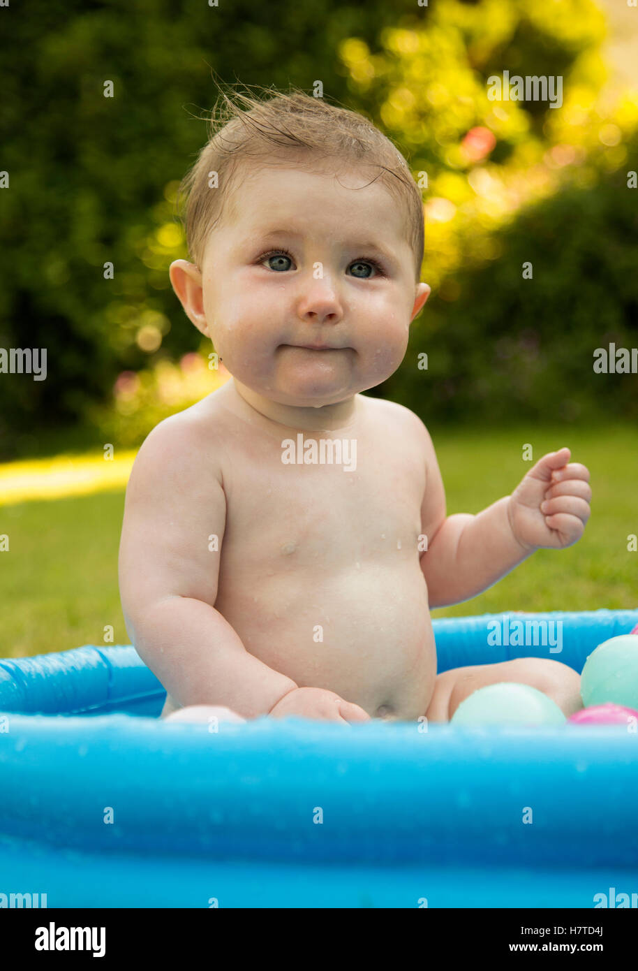 baby girl in a paddling pool in summer Stock Photo