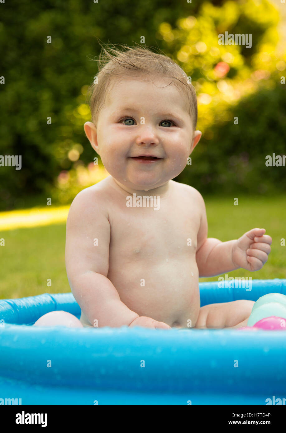baby girl in a paddling pool in summer Stock Photo