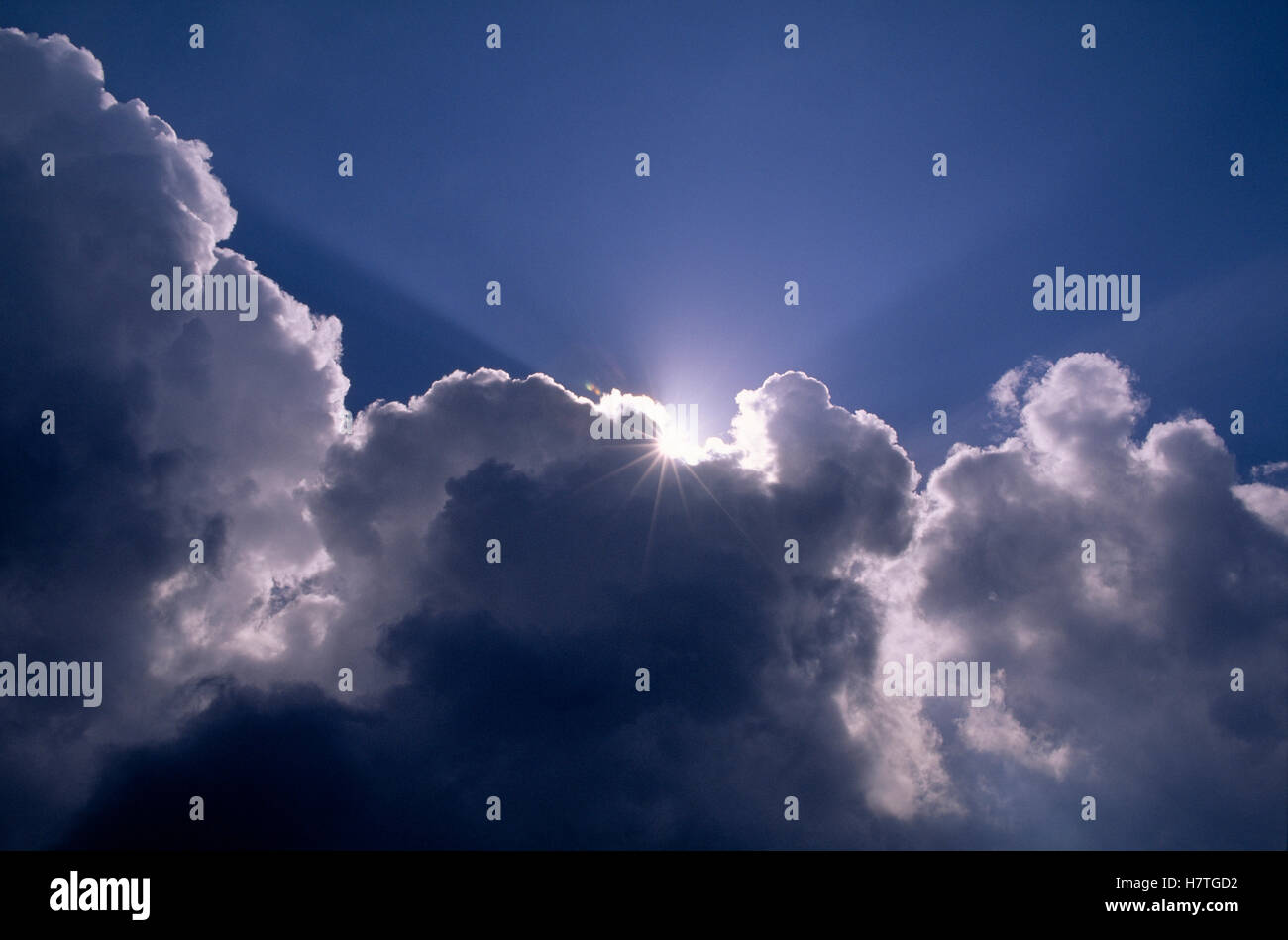 Sun behind cumulus clouds in a blue sky Stock Photo - Alamy