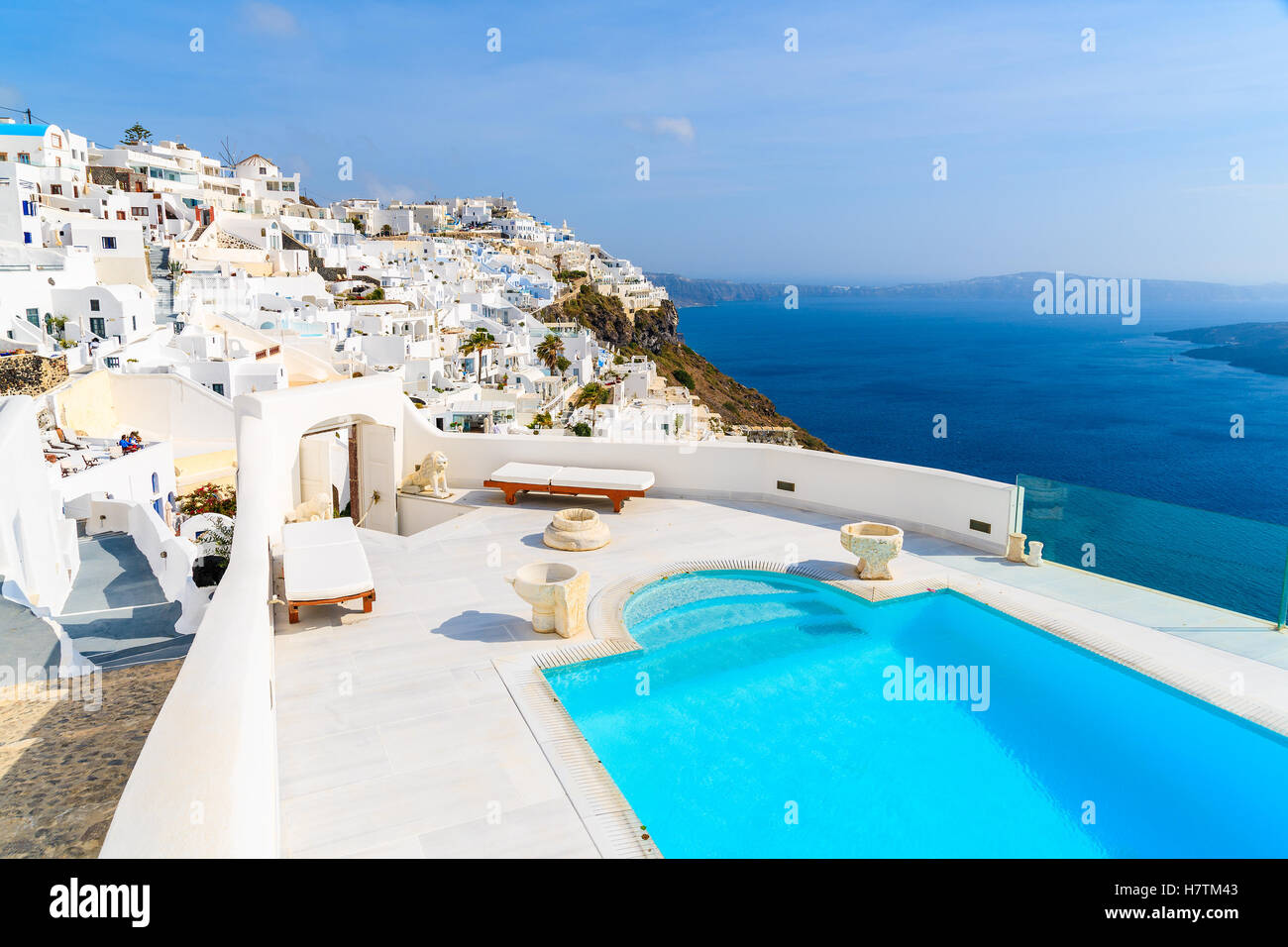 View of caldera and luxury swimming pool in foreground, typical white architecture of Imerovigli village on Santorini island, Greece. Stock Photo