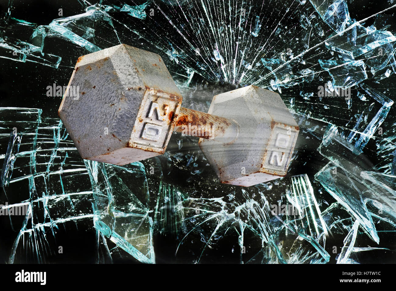 Dumbbell weight through broken glass window. Stock Photo