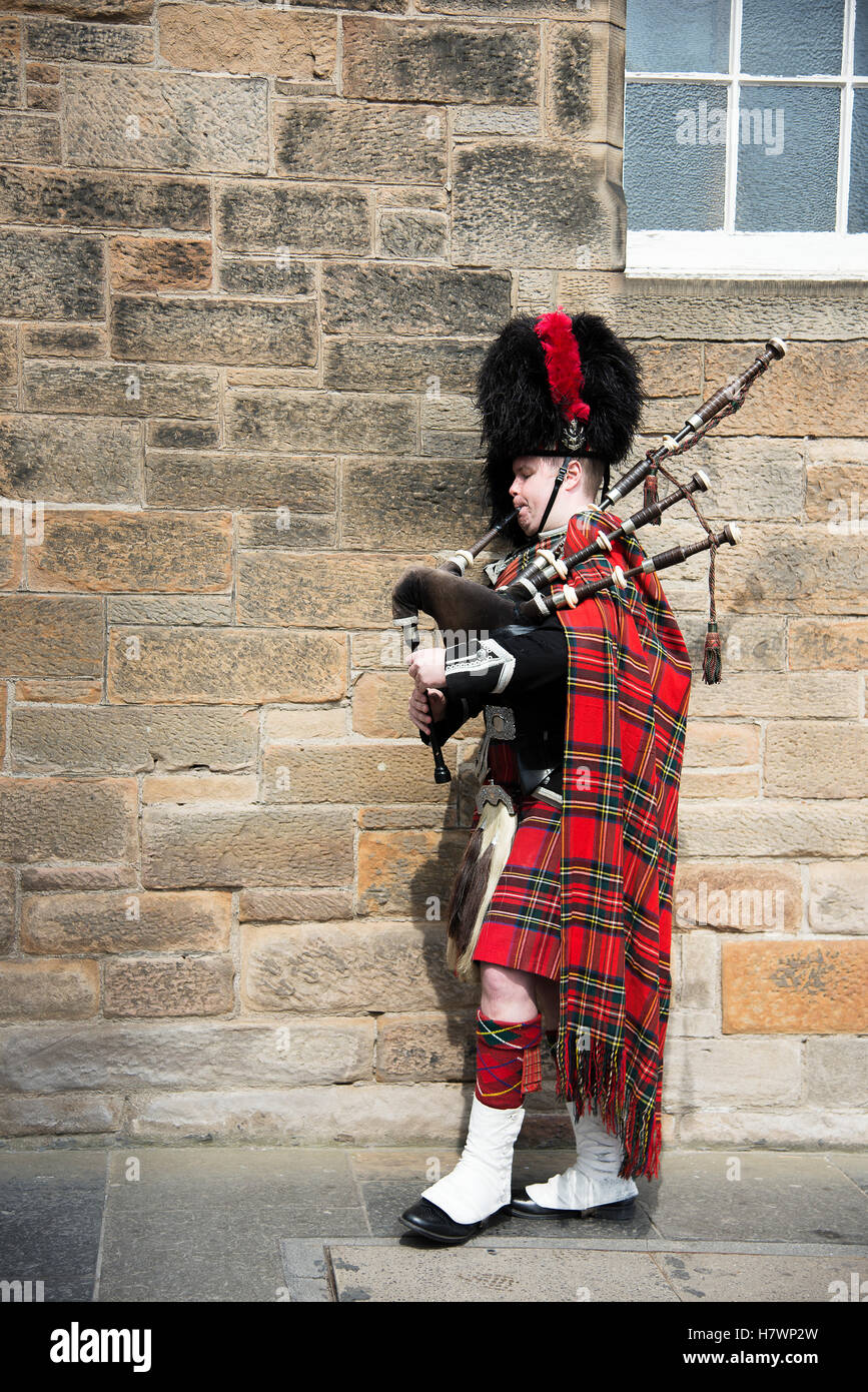 A man playing the bagpipes in full regalia, marching through Edinburgh's Old Town; Edinburgh, Scotland Stock Photo
