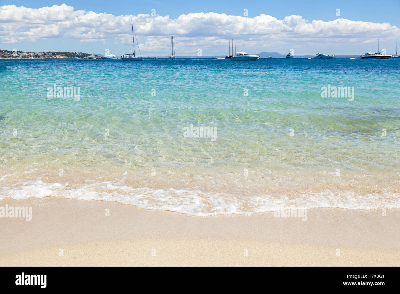 Palmanova Beach. Foamy waves lapping on the shore. In the distance are many sailers and yachts under the massive clouds. Spain Stock Photo
