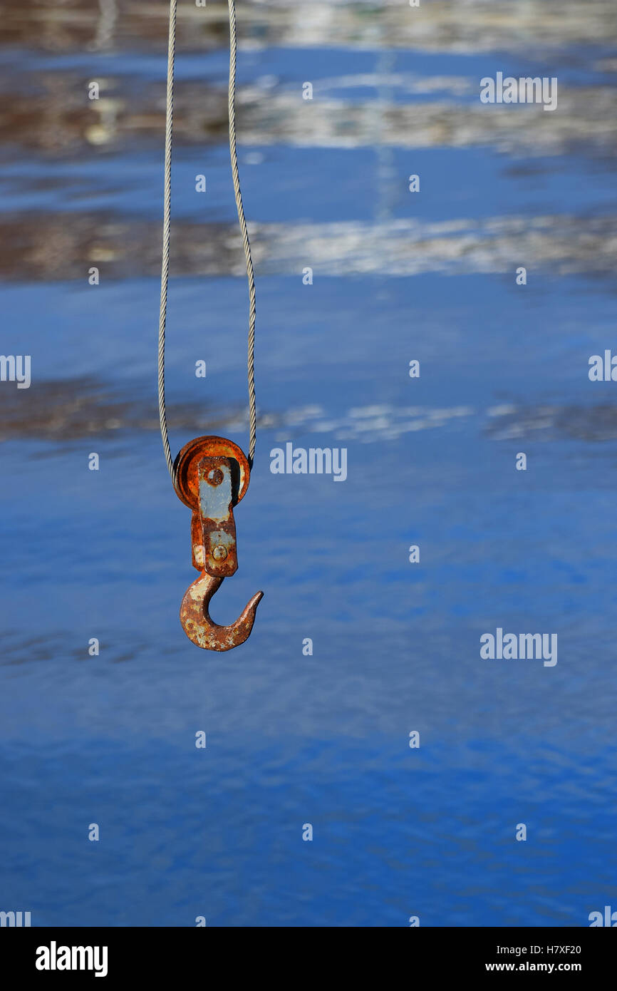 Rusty crane hook with blue sea on background. Stock Photo