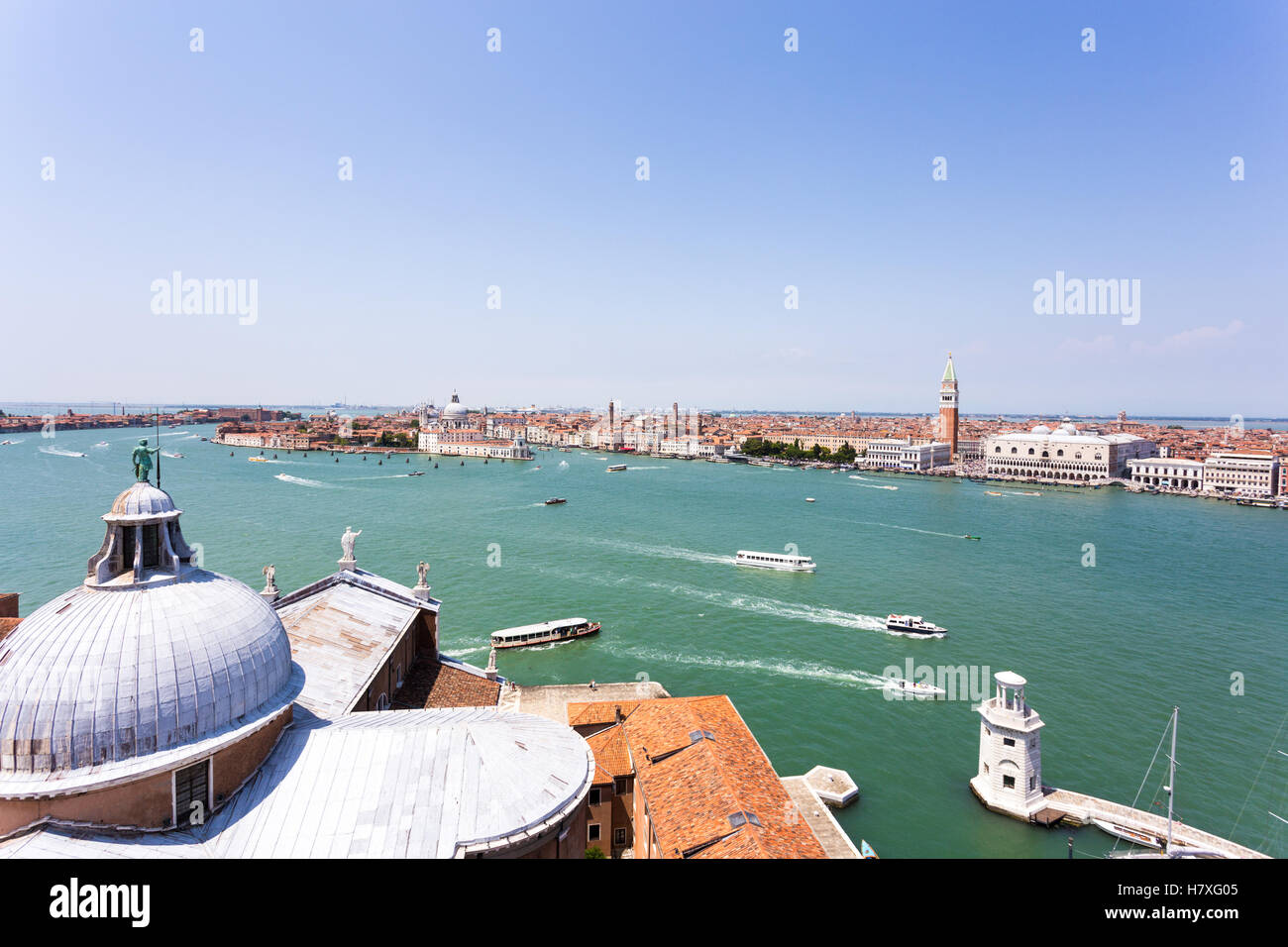 Boats navigating along the Grand Canal in Venice with the San Gorgio Cathedral in the foreground and the San Marco plaza on the  Stock Photo