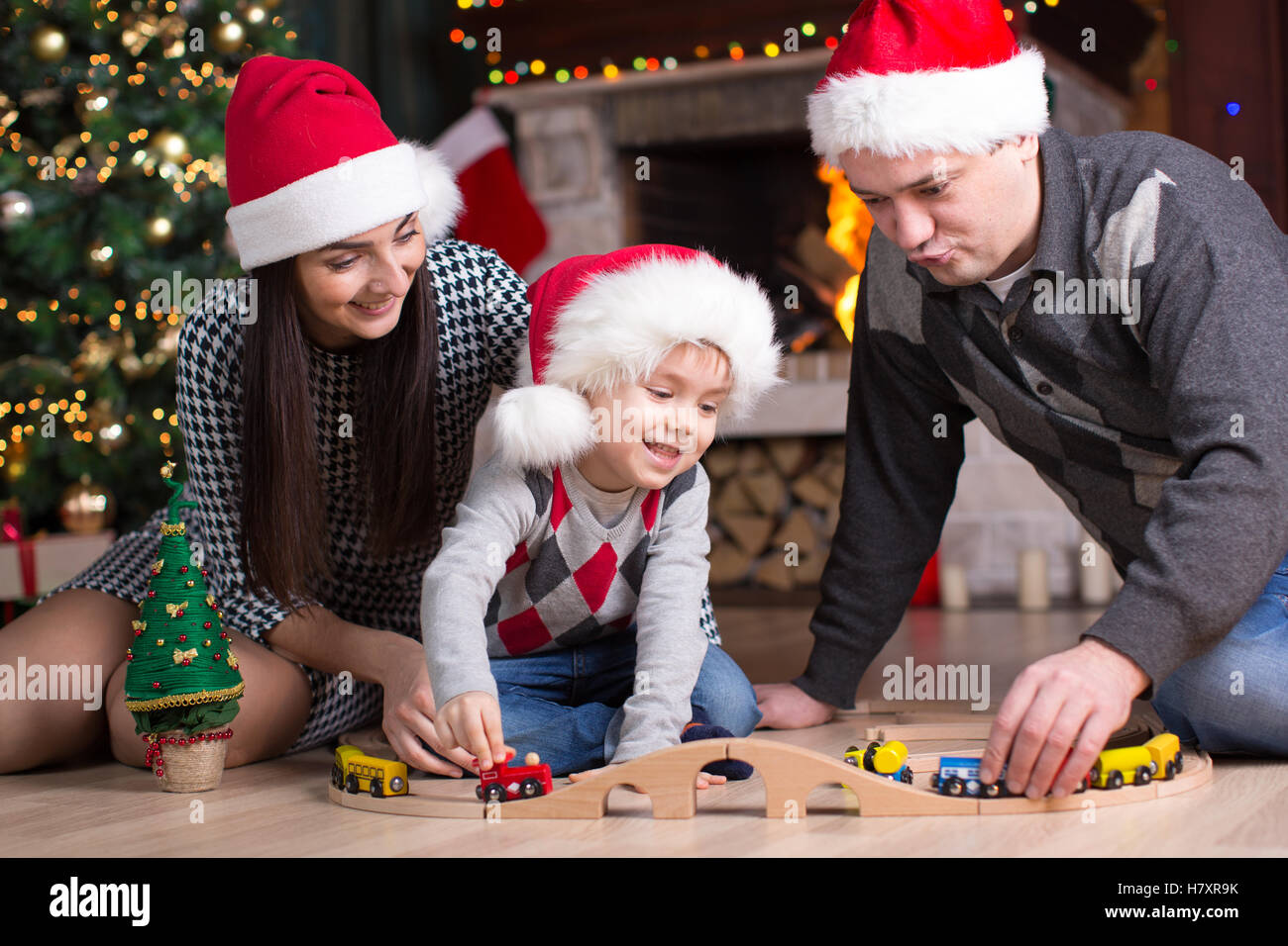 Father and mother with son play with model railway near christmas tree Stock Photo