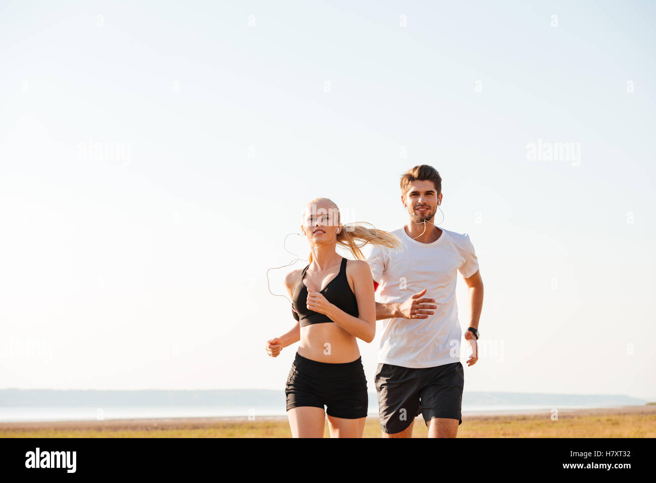 Smiling sports couple running together outdoors Stock Photo - Alamy