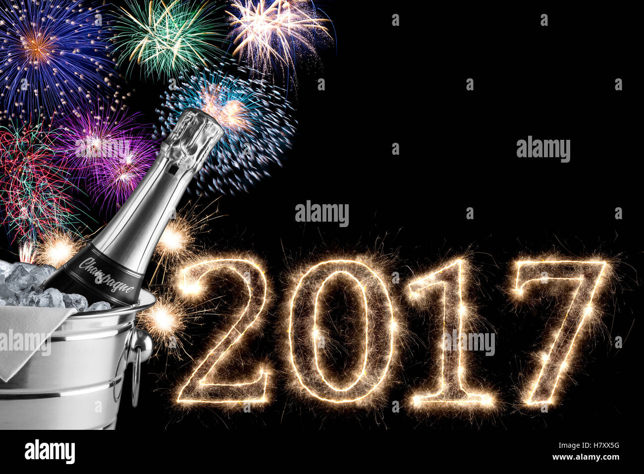 2017 colorful fireworks champagne bottle and cooler in the dark night sky with sparkling glowing number font lettering Stock Photo