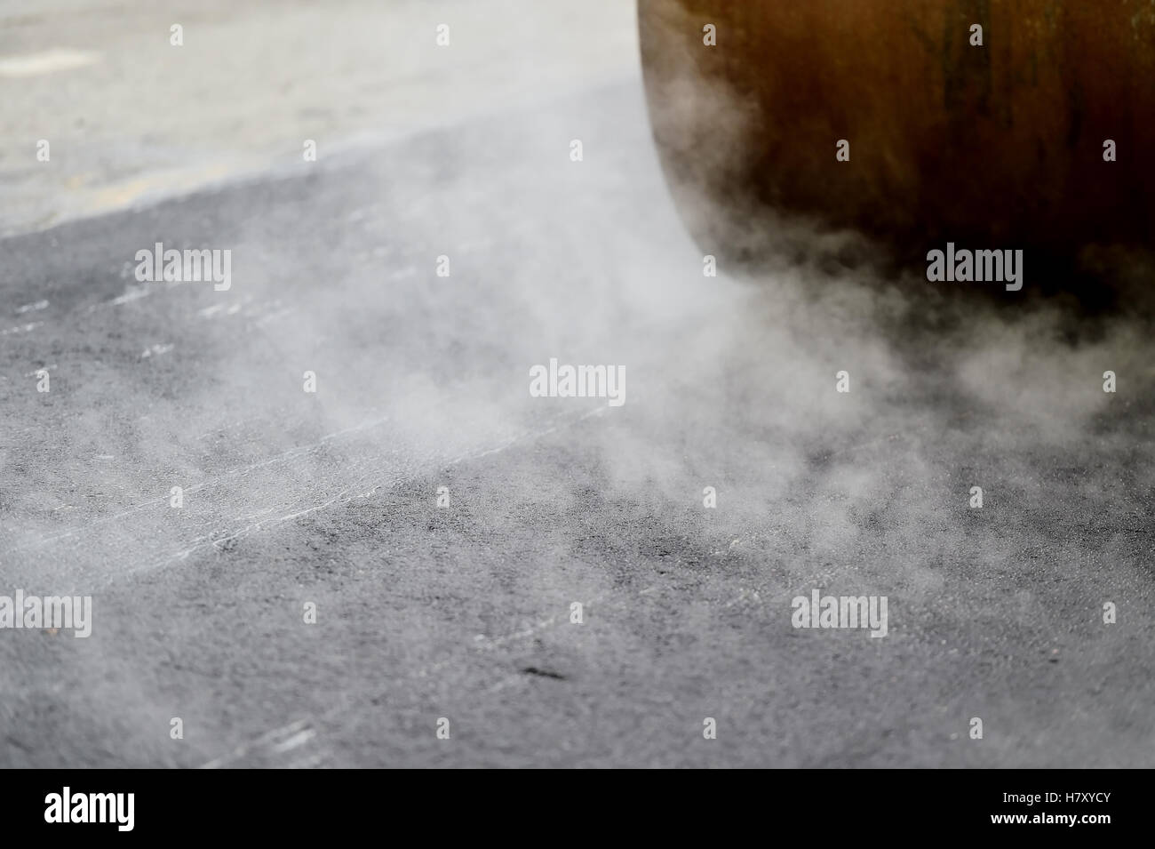 Asphalt paving with a steel wheel roller. Steam coming out from asphalt. Stock Photo