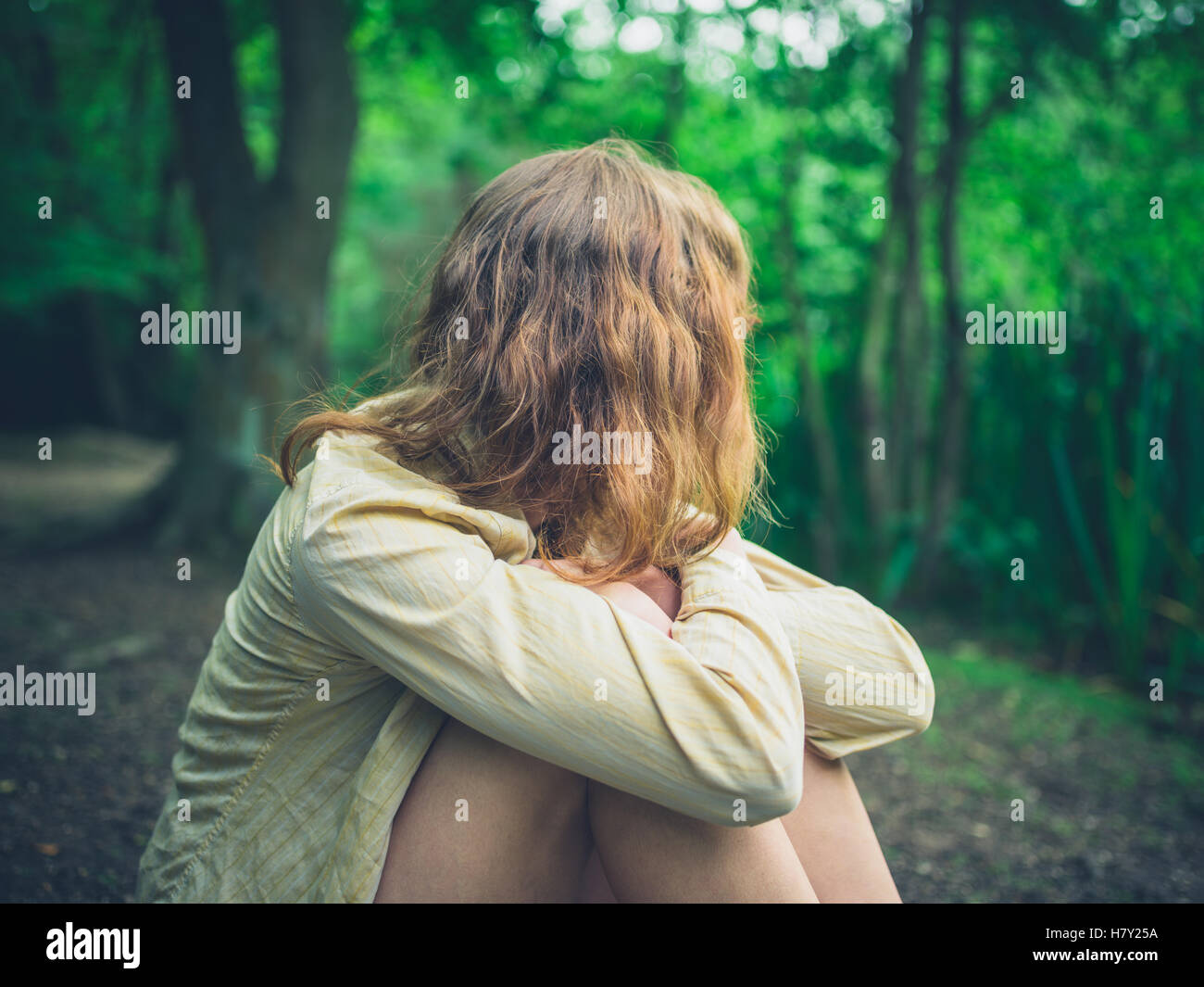 A young woman is sitting alone in the forest Stock Photo - Alamy