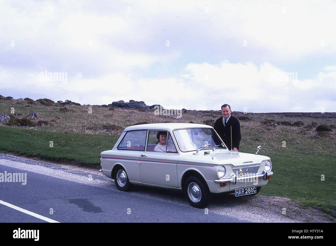 1960s, historical, a day out in the car. A couple with their small car a Singer (more commonly know as a Hillman) Imp, an innovative motor for the time, being a rear-engine and wheel-drive car and the small car rival to BMC's Mini. Stock Photo