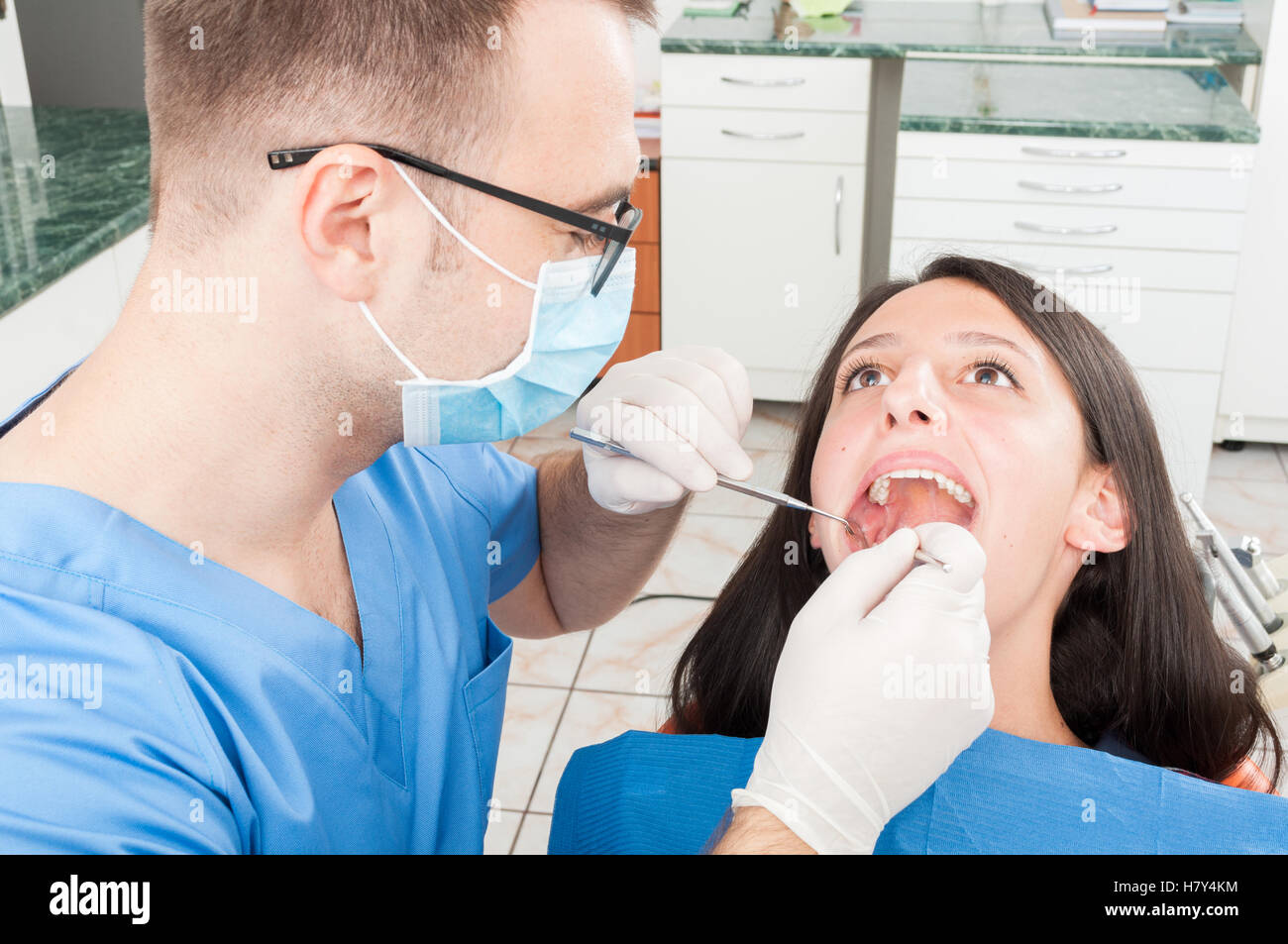 Lady sitting in dentist chair with mouth open and being checked Stock