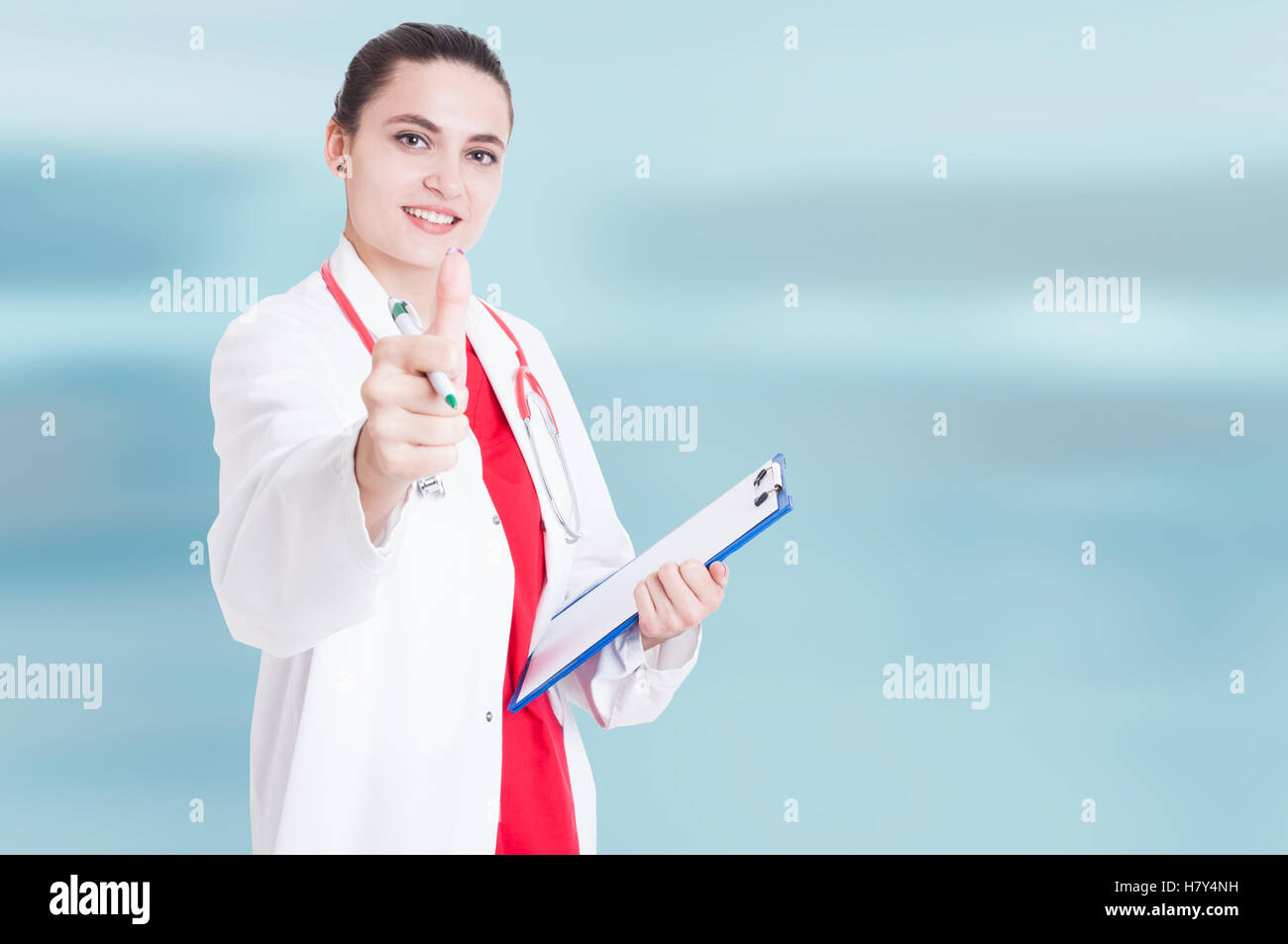 Happy female medic showing thumb up and holding clipboard isolated on ...