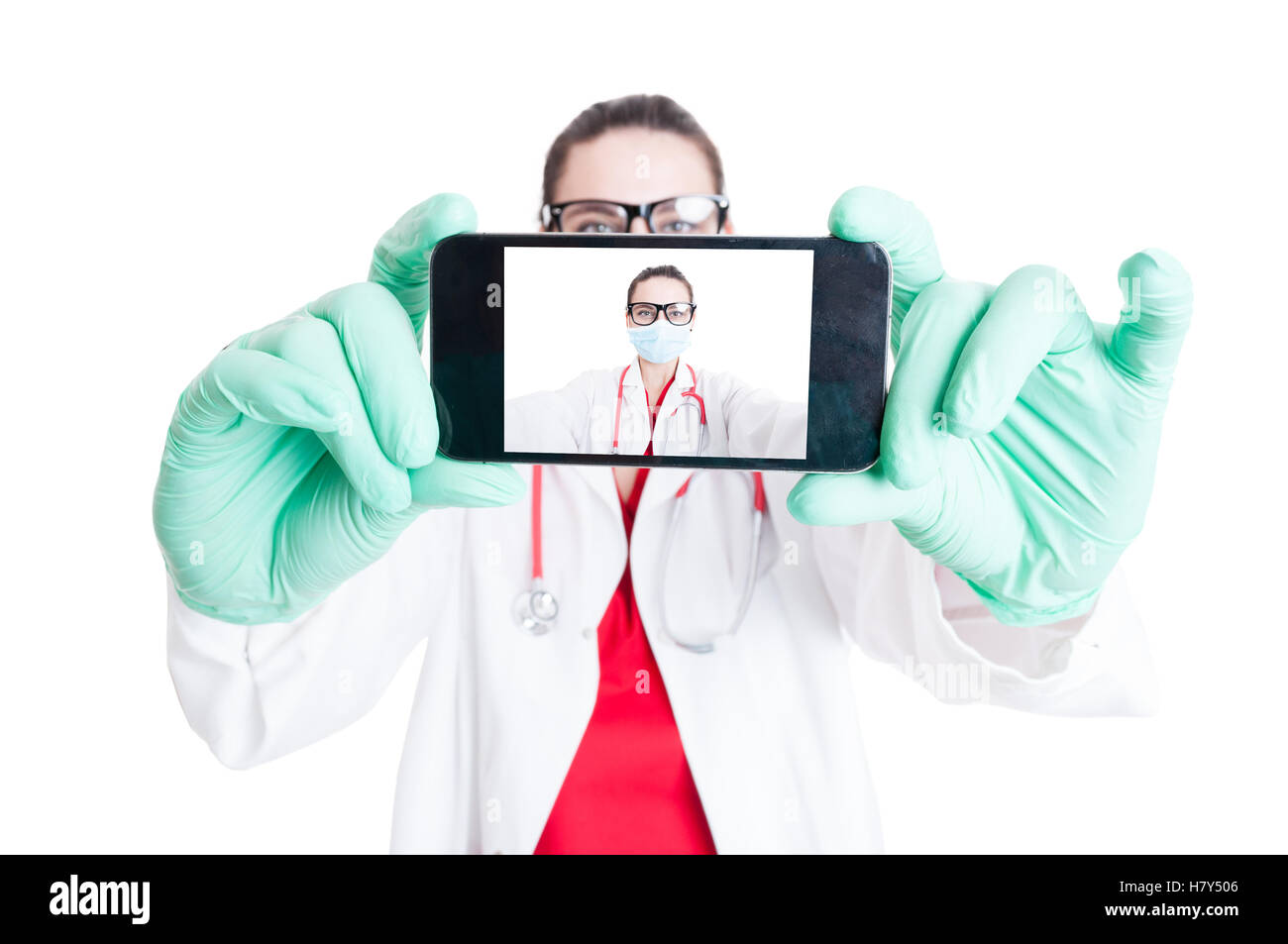 Woman doctor with googles and smartphone taking selfie on white studio background Stock Photo