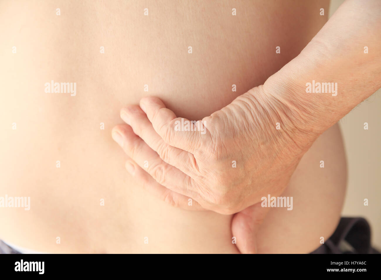 An older man reaches to the location of his backache. Stock Photo