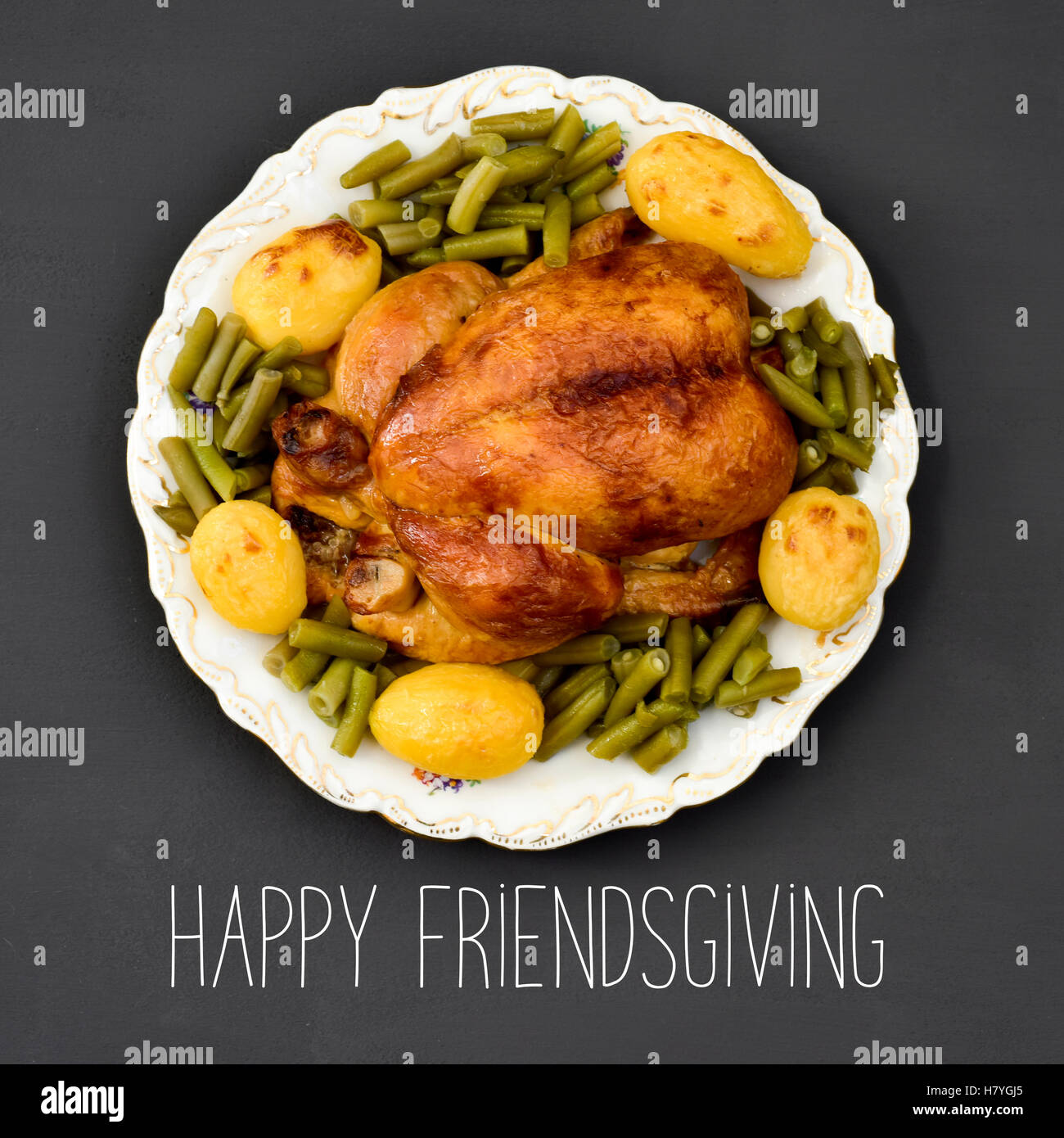 high-angle shot of a roast turkey on a round ceramic tray and and the text roast turkey and text happy friendsgiving on a dark g Stock Photo