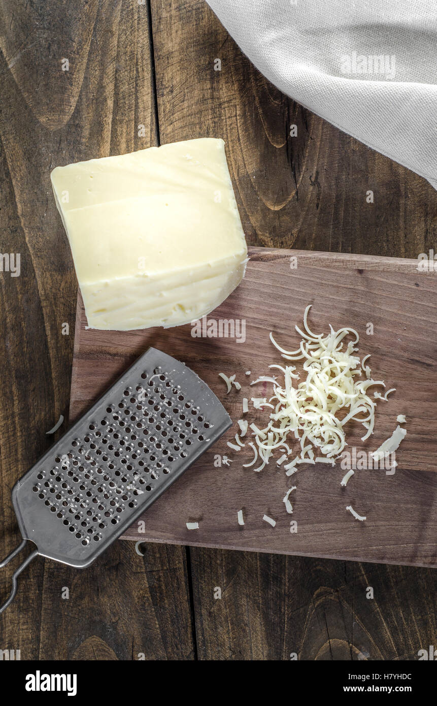 Cheese and grater on a wooden  kitchen table, from above Stock Photo