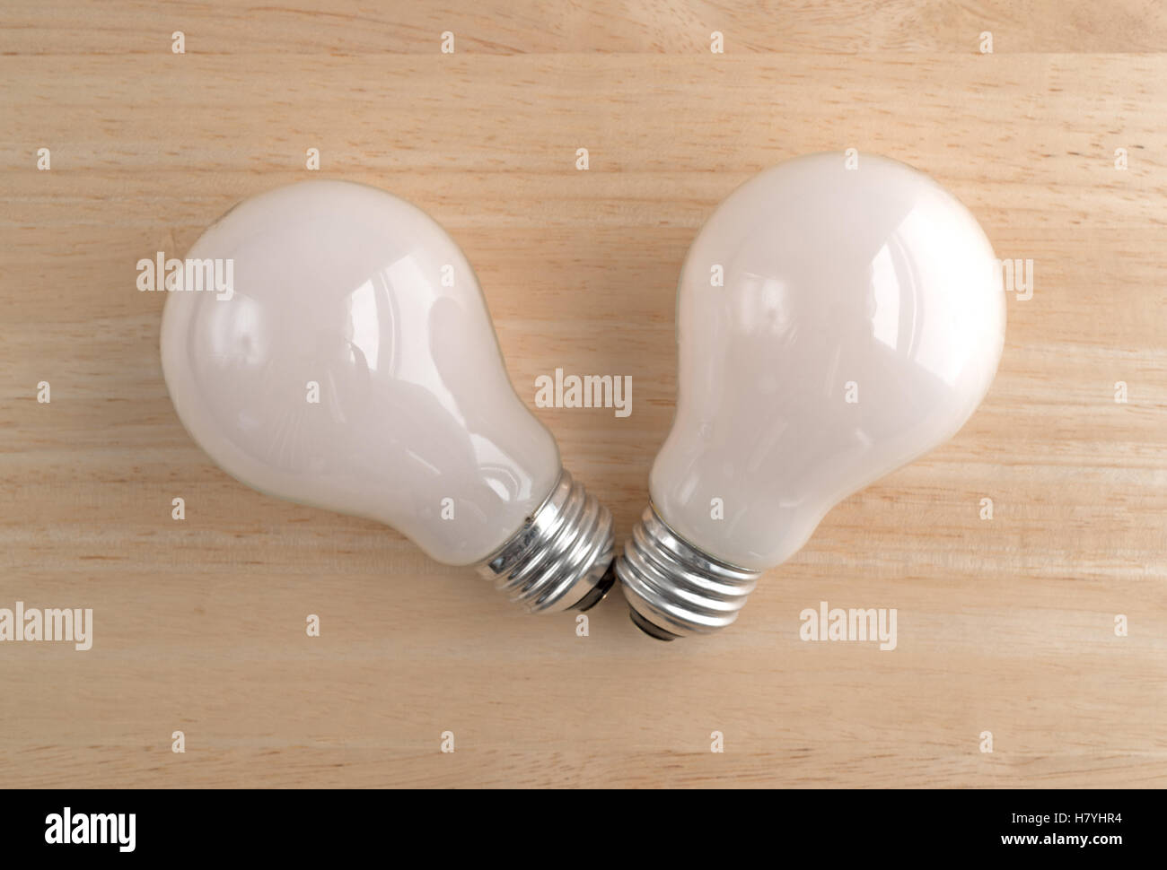 Top view of two soft white energy saving light bulbs on a wood table. Stock Photo