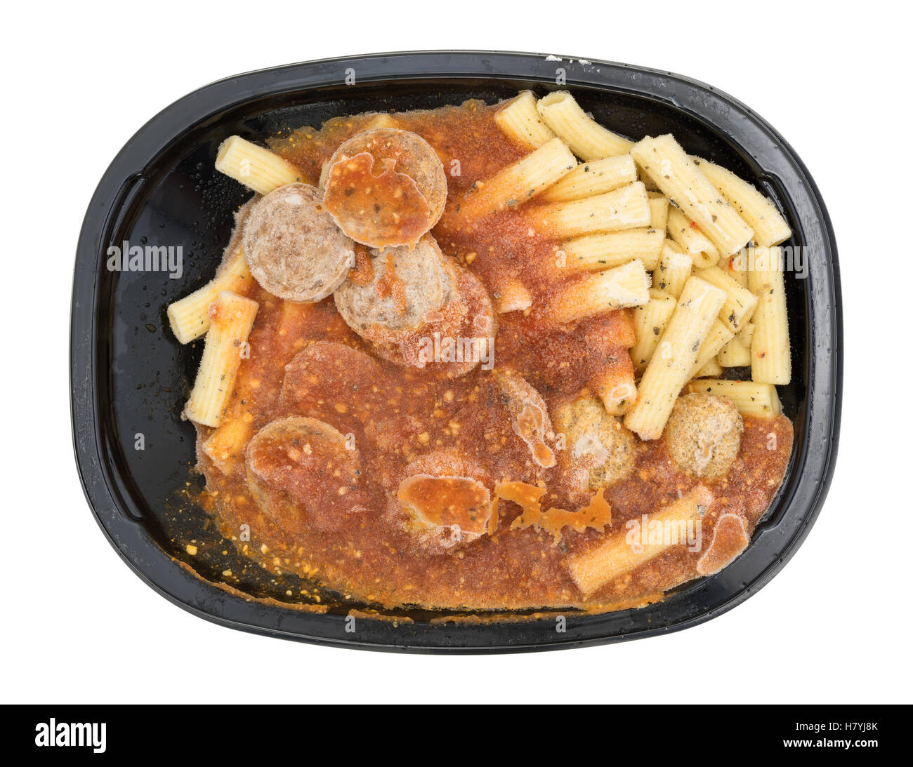 Top view of a frozen rigatoni pasta with sausage and meatballs in a marinara sauce TV dinner on a white background. Stock Photo