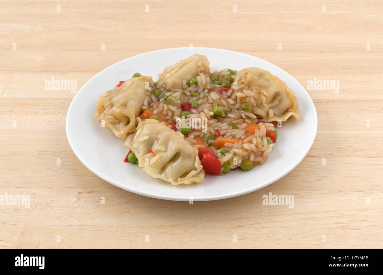 A microwaved vegetarian potstickers meal on a plate atop a wood table