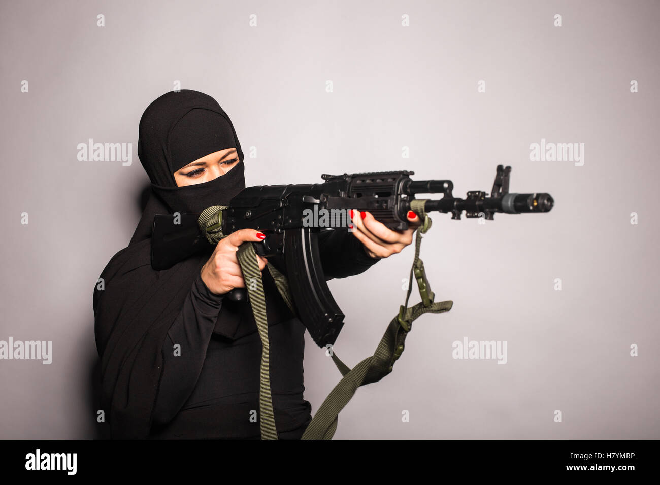 Muslim woman with a machine gun. An armed woman shoots. Islamic Woman holding an automatic weapon. Concept of war and terrorism Stock Photo