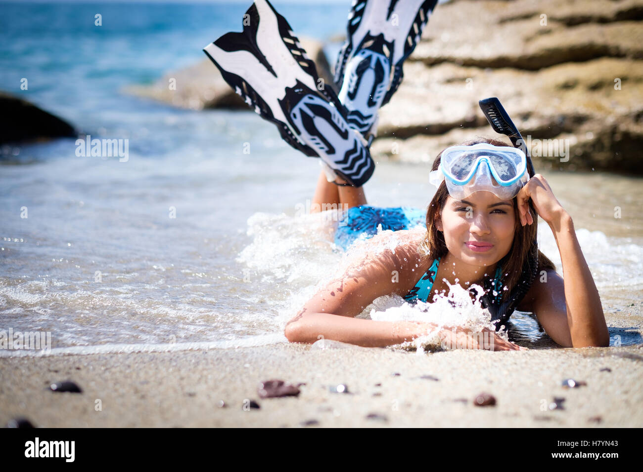 Snorkeling at the beach. Young woman with fins, diving mask, snorkel layed down, smiling. Stock Photo