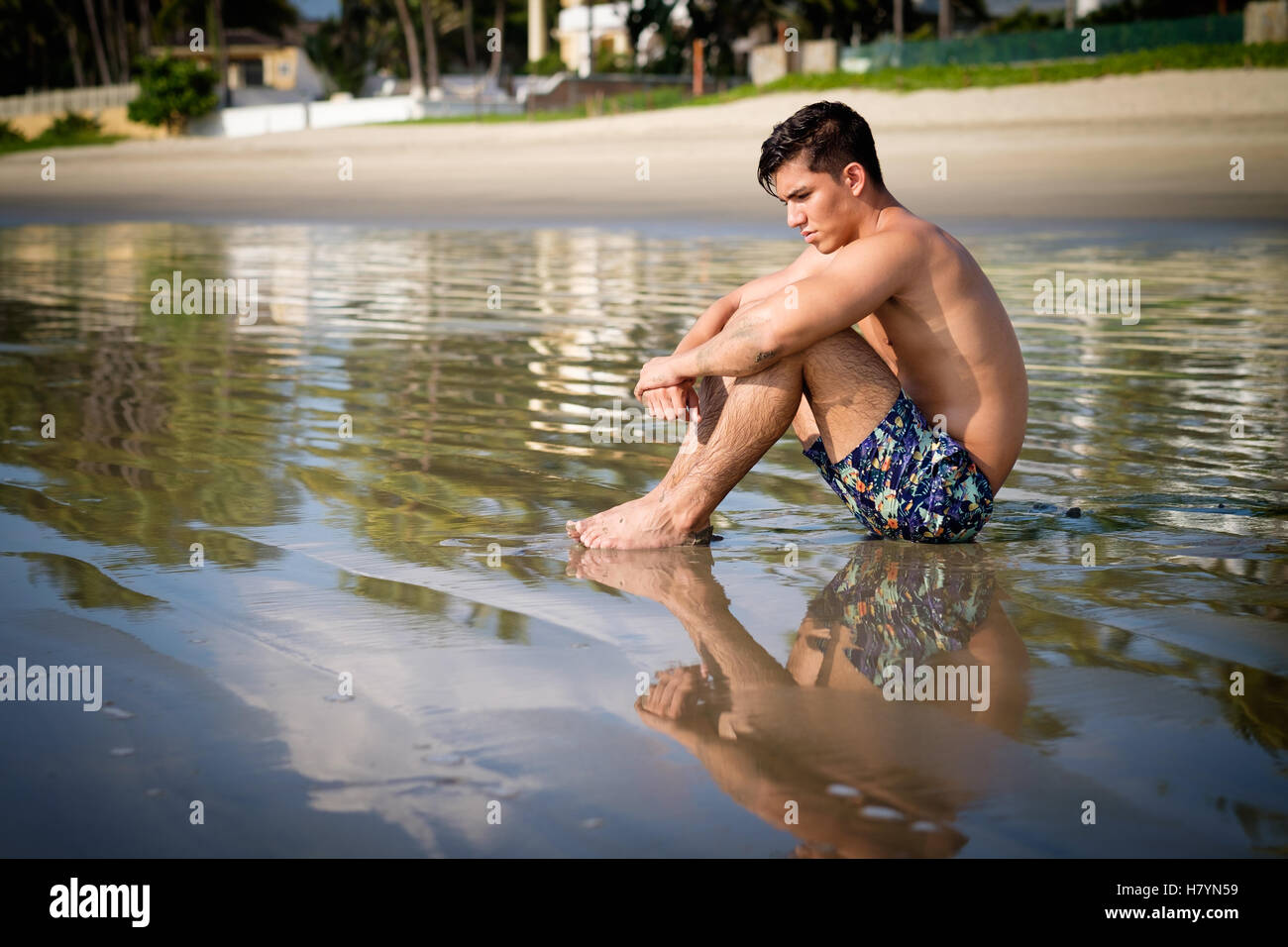 Young hispanic man in shorts sitting at a beach. Riviera Nayarit, Nuevo Vallarta, Mexico Stock Photo