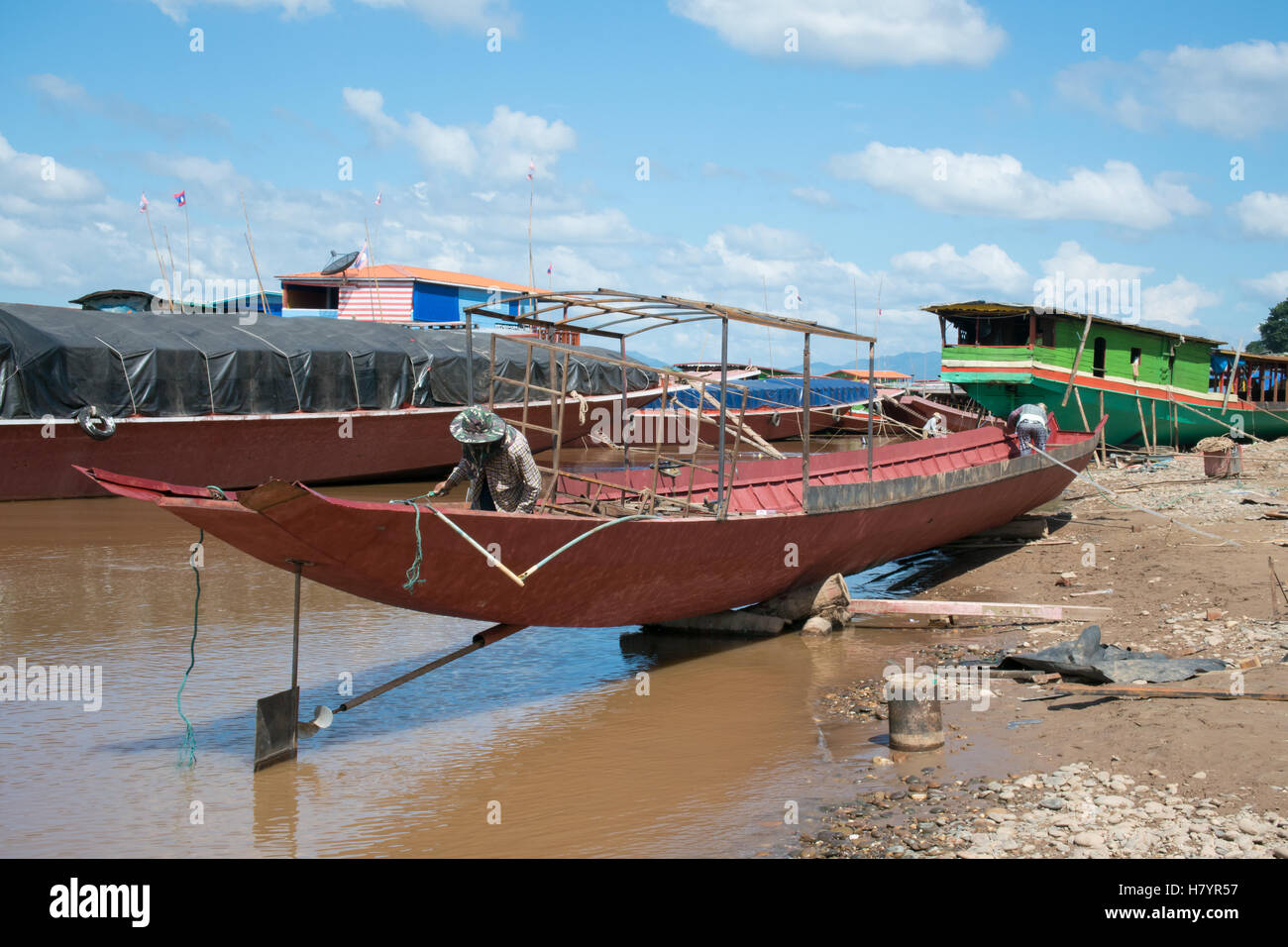 Undentified man and woman painting on unfinished iron boat,which park by Mae Khong river in Laos. Stock Photo
