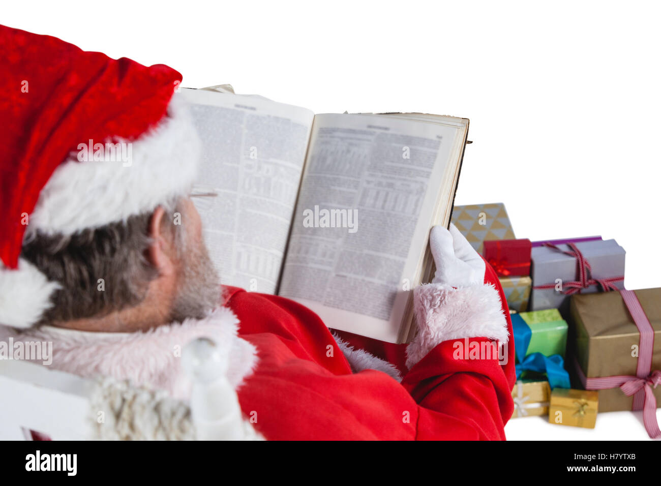Santa claus reading bible with christmas present beside him Stock Photo