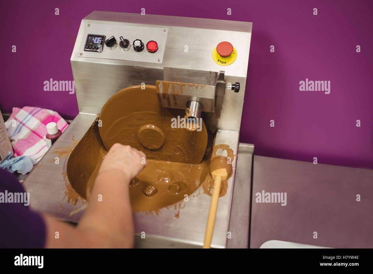 Worker dipping marshmallow in chocolate blending machine Stock Photo