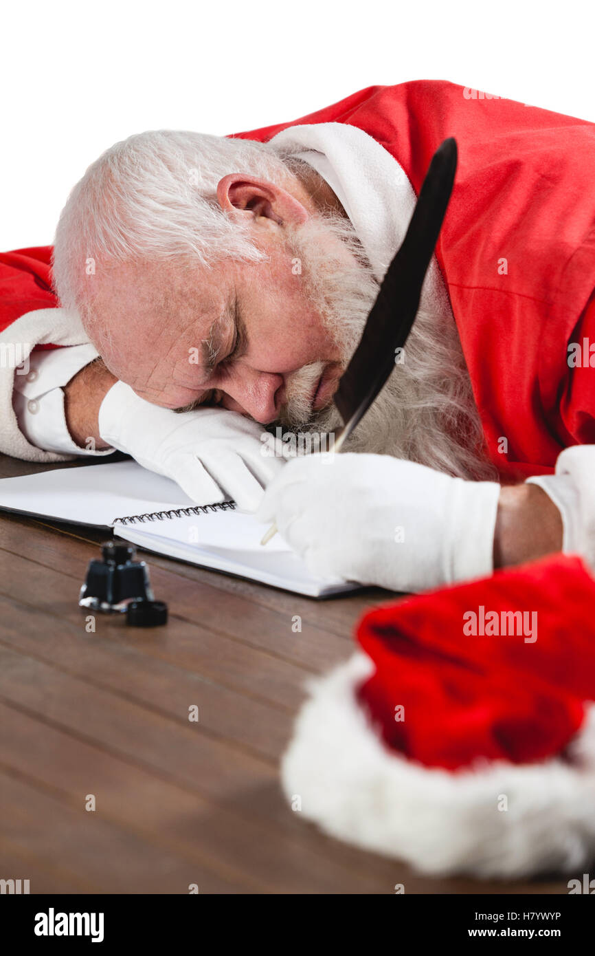 Santa claus sleeping at desk while writing a letter with a quill Stock Photo