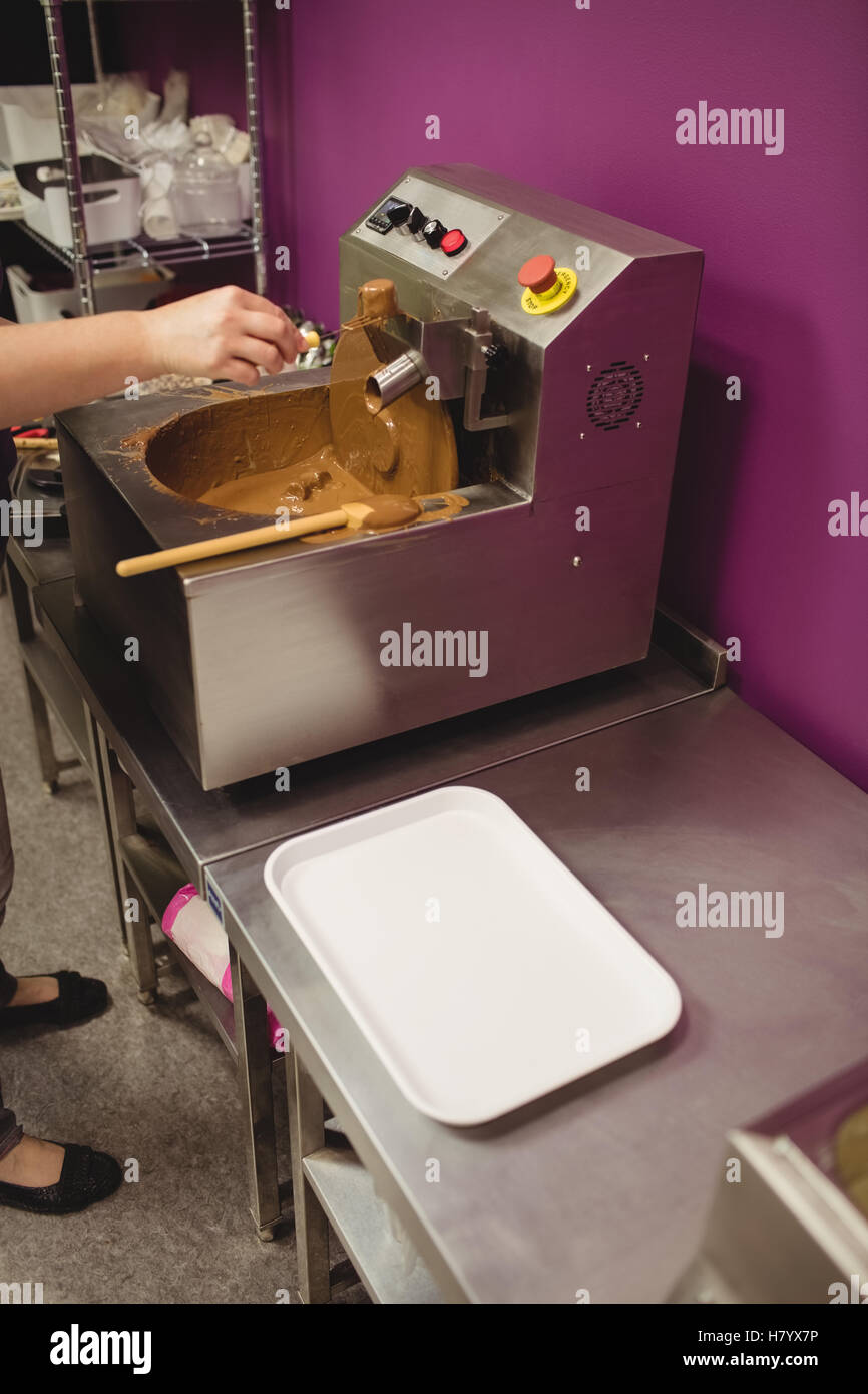 Worker dipping marshmallow in chocolate blending machine Stock Photo