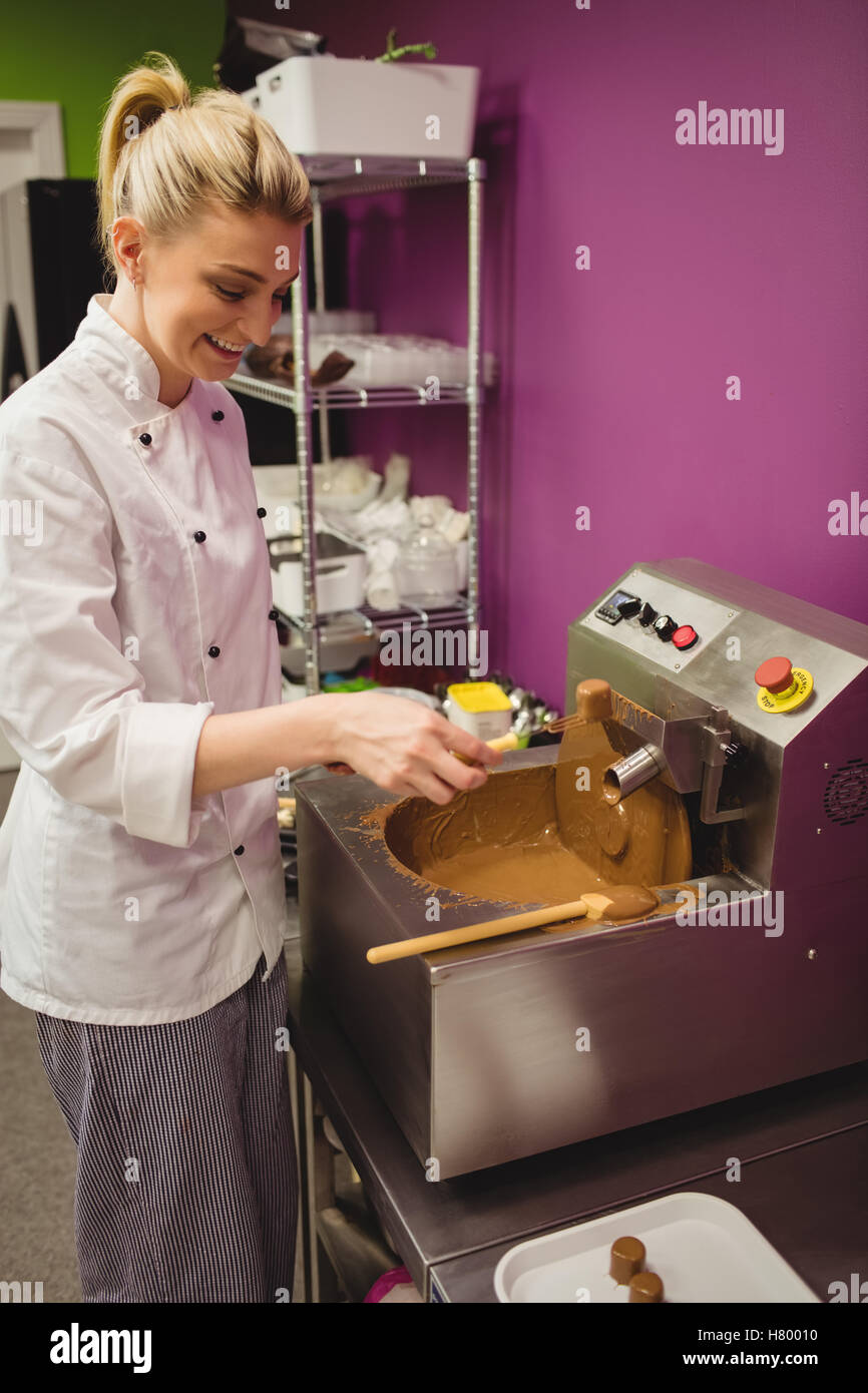 Worker dipping marshmallow in chocolate blending machine Stock Photo