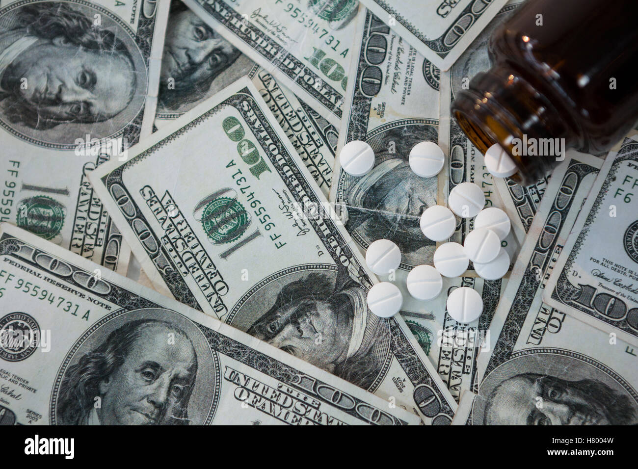 Pills spilling on currency notes Stock Photo