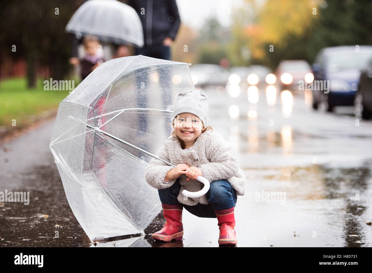 Little girl under the umbrella. Walk on rainy day. Stock Photo