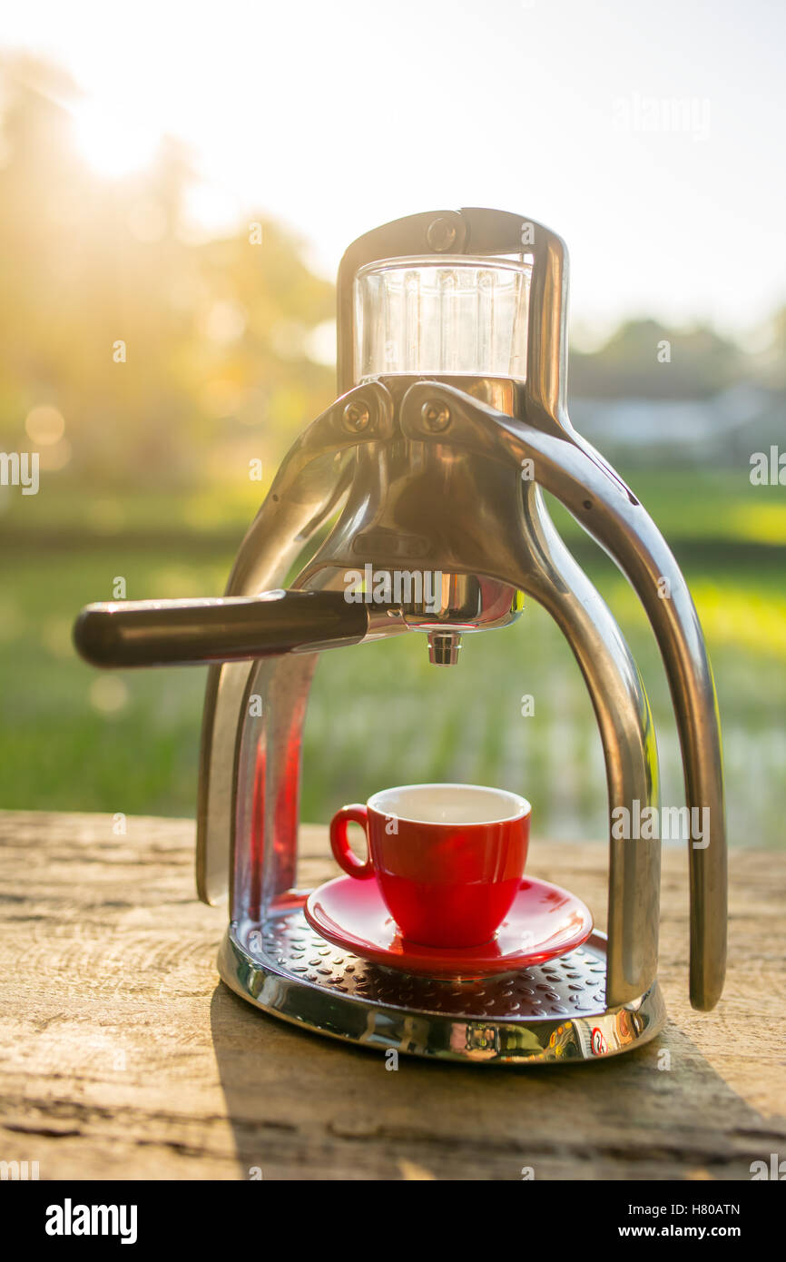 Manual old school espresso maker machine with a cup on wooden table in
