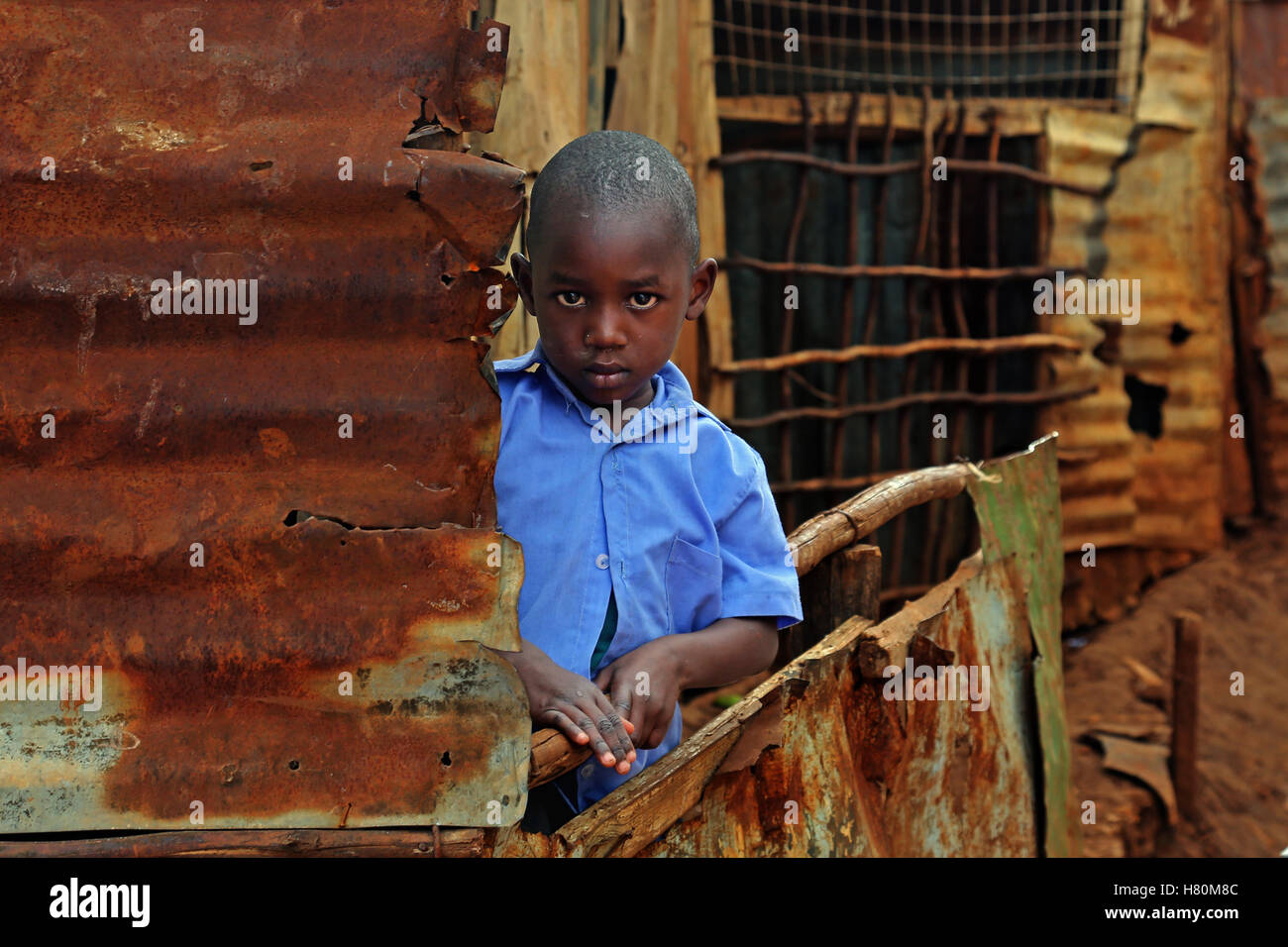 Boy standing between rusty houses in Kibera Slum, Nairobi, Kenya Stock Photo