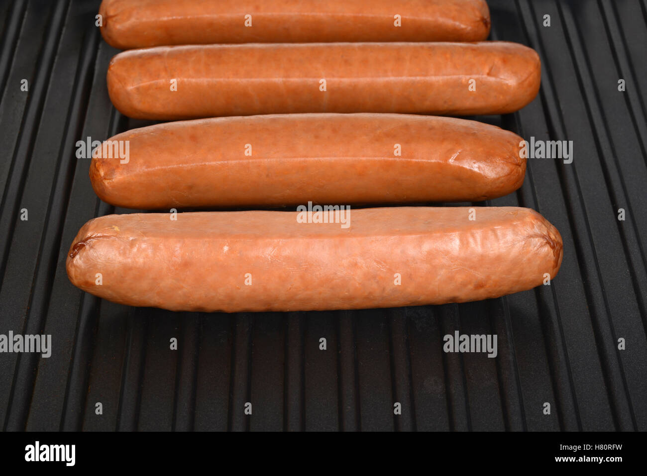 cooking sausages on a black grill Stock Photo
