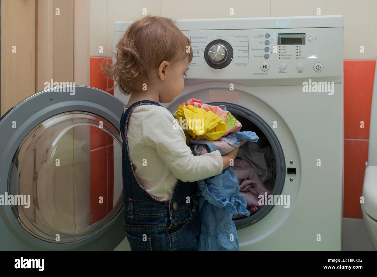 small child puts laundry in the washing machine. Mother's helper. 2