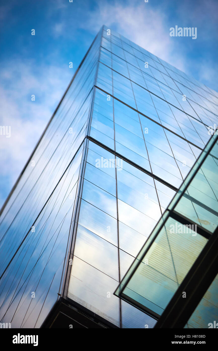 Blue sky and clouds reflected in glass windows of modern office ...