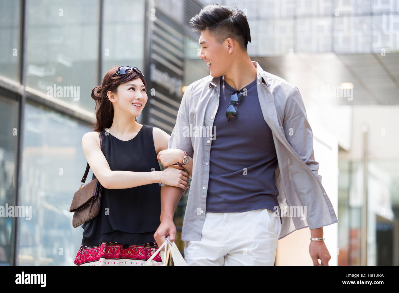 Happy young Chinese couple walking with shopping bags Stock Photo - Alamy